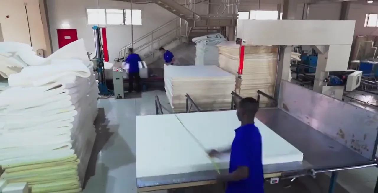 A worker cutting foam sheets to size for mattresses